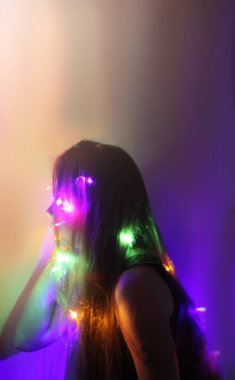 A girl holds beautiful bright lights in her hands. Child playing with magic lights at home.