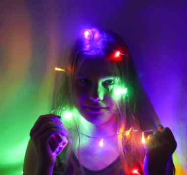 Bir kız elinde güzel parlak ışıklar tutar. Evde sihirli ışıklarla oynayan çocuk.