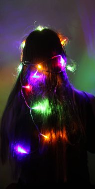 Bir kız elinde güzel parlak ışıklar tutar. Evde sihirli ışıklarla oynayan çocuk.