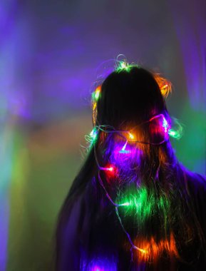 Bir kız elinde güzel parlak ışıklar tutar. Evde sihirli ışıklarla oynayan çocuk.