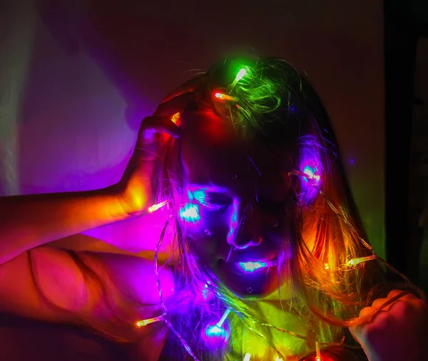 Bir kız elinde güzel parlak ışıklar tutar. Evde sihirli ışıklarla oynayan çocuk.