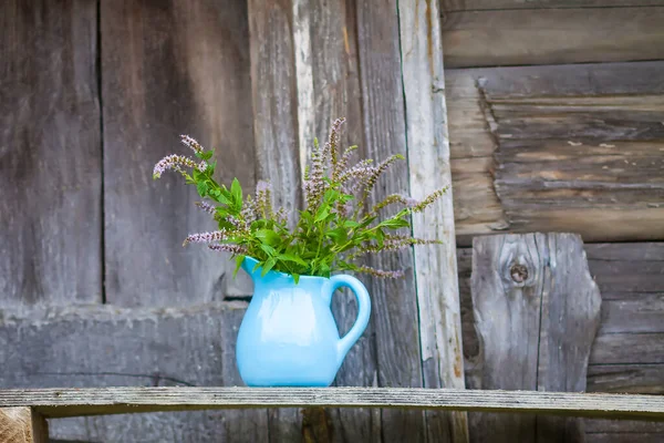 Bitki çayı için taze organik çiçek açan nane bitkileri. Şifalı bitkiler. Mavi seramik sürahi içinde bir buket tıbbi çiçek.
