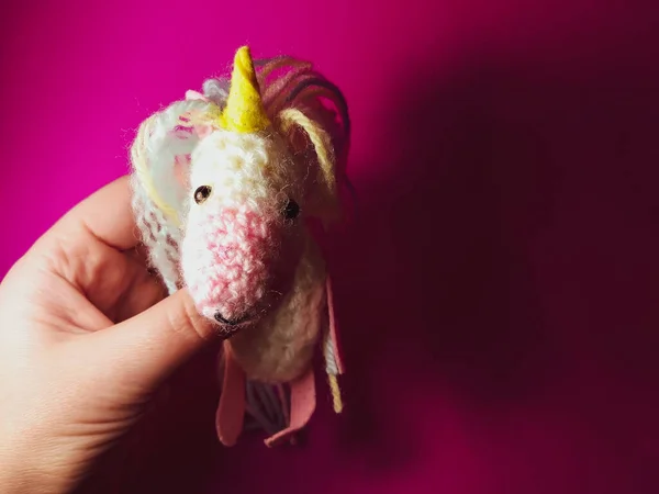 A knitted unicorn. A soft handmade toy for a child.