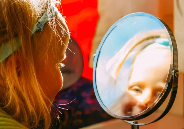 Little girl looking at the reflection in the mirror.
