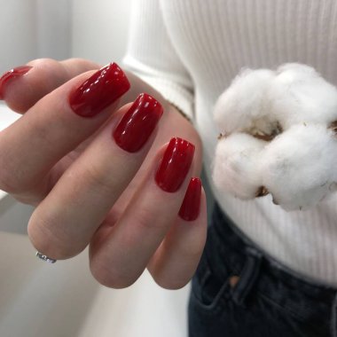 Kırmızı manikür. Tırnaklarında kırmızı manikür olan bir kadının elleri. Manikür güzellik salonu konsepti. Metin veya logo için boş yer.