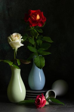 Koyu arkaplanlı vazolarda güller olan modaya uygun bir kompozisyon. Yaratıcı hala hayat konsepti. Boşluğu kopyala.