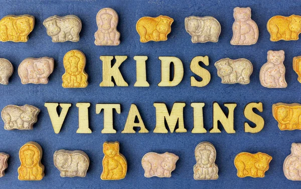 Multi-colored children\'s vitamins in the form of animals on a blue background. The phrase \