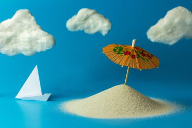 Kokteyller için kağıt şemsiyeler kumsalda beyaz bulutlar. Kopyalama alanı olan yaratıcı yaz konsepti.