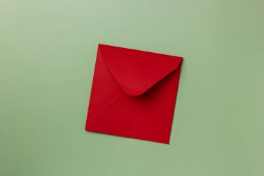 Yeşil arka planda kırmızı kağıt zarf. Düz yerde, üst tarafta. Sevgililer günü için mektup, yeni yıl, anneler günü, kadınlar günü..