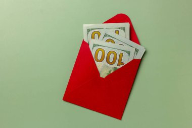 Kırmızı zarfta 100 dolarlık banknotlar. Zenginlik kavramı, büyük kar ya da yeni yıl hediyesi. Kopyalama alanı olan düz. 