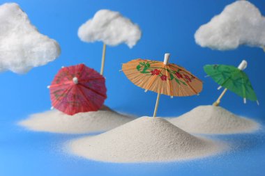 Kumda kokteyller ve sahilde beyaz bulutlar için kağıt şemsiyeler. Kopyalama alanı olan yaratıcı yaz konsepti.