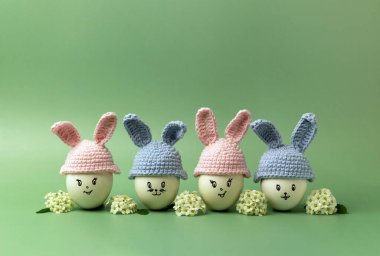 Yeşil arka planda yumurta ve çiçeklerden yapılmış Paskalya tavşanları ile yaratıcı kompozisyon. Mutlu Paskalyalar. Boşluğu kopyala.