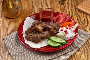 Geleneksel Rus şiş kebap ızgara şiş ve ahşap bir masada sebzeler.