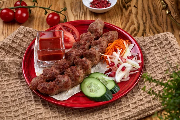 Ahşap bir masanın tepsisindeki lezzetli lula kebabı. Tahta şişte doğranmış et, ızgara. Doğu mutfağı.