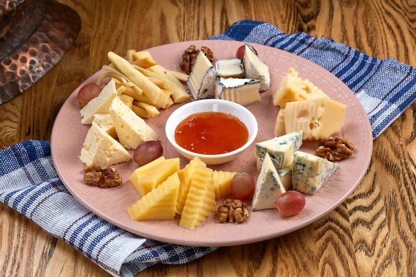 Cheese plate. Delicious cheese mix with walnuts, jam on wooden table. Tasty cheese starter for wine. — Stock Photo, Image