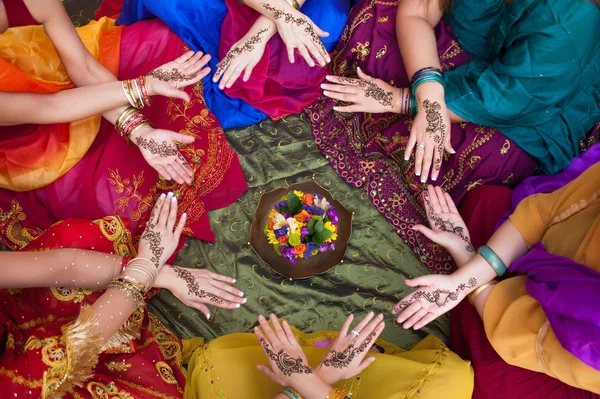 Six pairs of henna decorated female hands arranged in a circle on a colorful background. — Stock Photo, Image