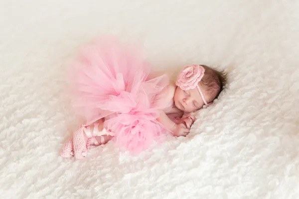 Schlafendes neugeborenes Mädchen mit rosa gehäkeltem Stirnband und Tutu. — Stockfoto