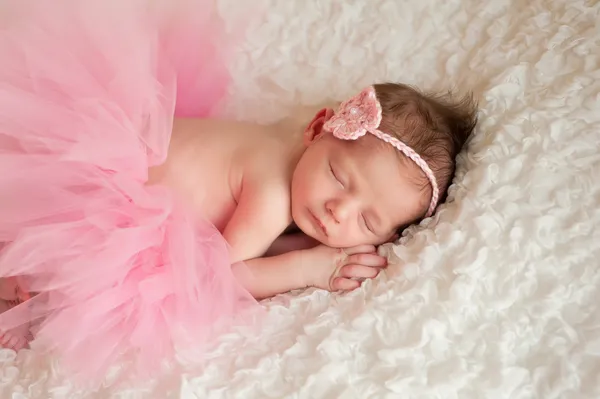 Nyfödd baby flicka klädd i en rosa virkade pannband och tutu. — Stockfoto