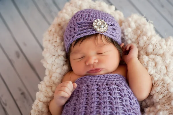 Sleeping newborn baby girl wearing a fancy, lavender flapper style crocheted hat. — Stock Photo, Image