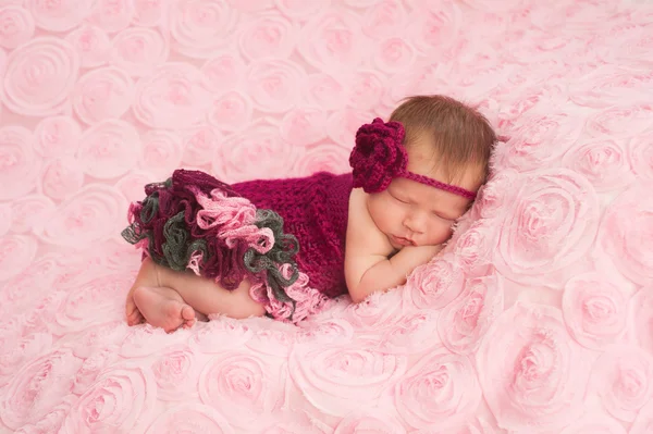 Una niña recién nacida durmiendo con una diadema de ganchillo marrón y mameluco . —  Fotos de Stock