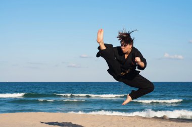 kadın, dördüncü derece, taekwondo siyah kuşak sporcu gerçekleştiren bir havada tekme sahilde atlama.
