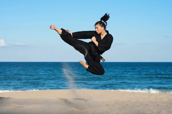 kadın, dördüncü derece, taekwondo siyah kuşak sporcu gerçekleştiren bir havada tekme sahilde atlama.