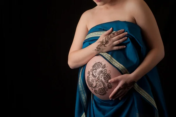 Henna-Tätowierpaste auf Händen und Schwangerschaftsbauch einer Frau. — Stockfoto