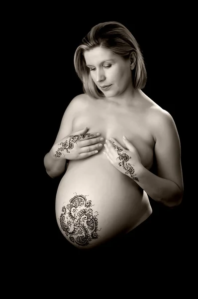 Henna tatoeage plakken op een vrouw handen en zwangere buik. — Stockfoto