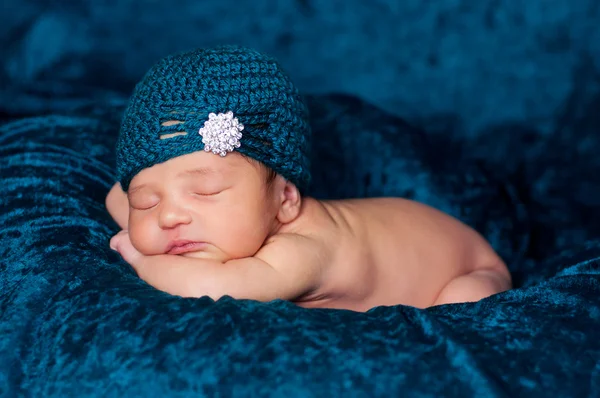 Menina recém-nascida dormindo em um cobertor teal e vestindo um chapéu de malha flapper-estilo teal com enfeite de strass . — Fotografia de Stock