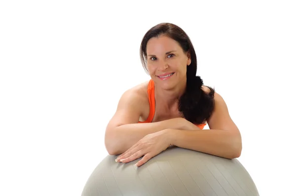 Mujer morena apoyada en una pelota de ejercicios de Pilates gris . — Foto de Stock