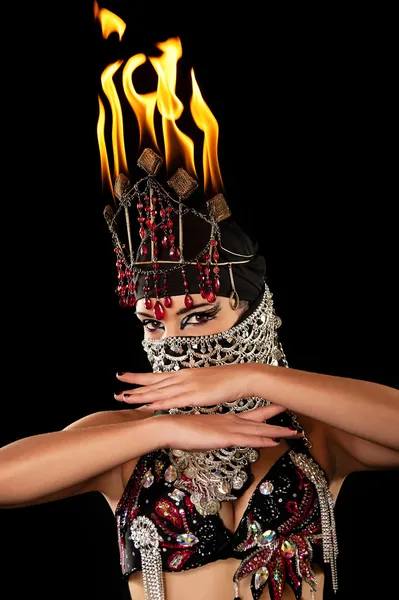 Tête et épaules tournées d'une danseuse exotique portant un costume rouge et noir avec hijab et coiffe de feu — Photo