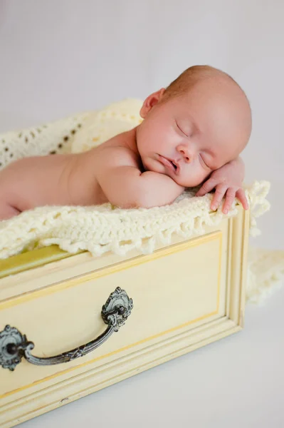 Newborn baby girl sleeping in a vintage yellow drawer. — Stock Photo, Image