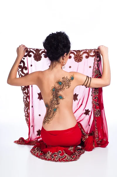 Mujer sosteniendo un sari rojo. Ella tiene un diseño de henna de plumas de pavo real en su espalda . — Foto de Stock
