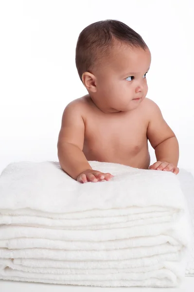 Bébé garçon derrière une pile de serviettes blanches — Photo