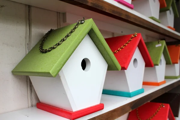 Casas de pájaros rústicas hechas a mano con techos de colores brillantes y cadenas de eslabones para colgarlos alrededor del patio para atraer a nuestros amigos emplumados a anidar . Imagen de archivo