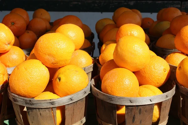 Cestas de madeira simples com várias laranjas frescas e suculentas no mercado local do agricultor Imagens De Bancos De Imagens