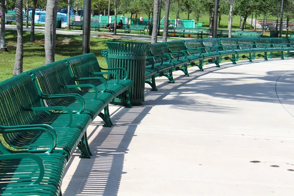 Snyggt och välordnat semi cirkla ordningen av grön metall bänkar i parken Stockbild