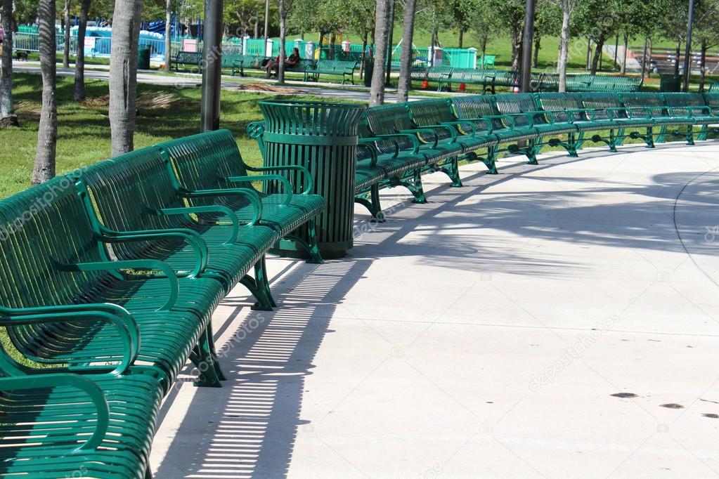 Neat and orderly semi circle arrangement of green metal benches in the park