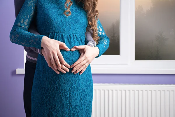 Het hart op een zwangere vrouw buik — Stockfoto