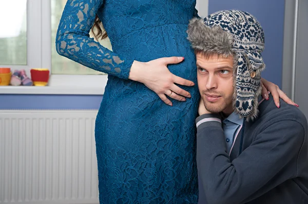 De man probeert te luisteren zijn vrouw buik — Stockfoto