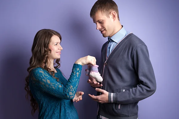 女性は彼女の男に将来の赤ちゃんの bootees を与えています。 — ストック写真