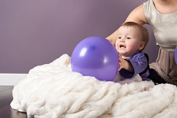 Ein kleines Mädchen spielt mit violettem Luftballon — Stockfoto