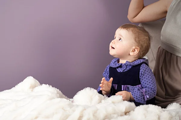 Une petite fille lève les yeux tandis que sa mère est assise derrière elle — Photo