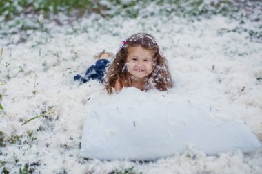 Kuş tüyü yastık dağınıklığı ve mutlu küçük kız tarlada