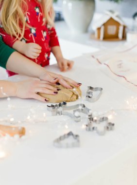 Noel pişirme geçmişi: Hamur, kurabiye kesme makinesi ve Noel süslemeleri. Beyaz bir masada Noel kurabiyeleri. Kadın ve kız Noel kurabiyesi yapıyorlar.