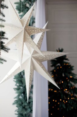 Noel ağacının ve Noel süslemelerinin yakınındaki bir pencerede asılı beyaz kağıt Noel yıldızları