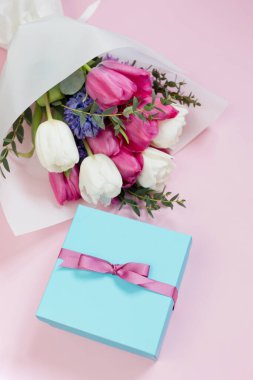 Güzel bir buket ve pembe arka planda kurdeleli mavi hediye kutusu. Fotokopi alanı ile tatil konsepti, metin için yer. 8 Mart, anneler günü teması