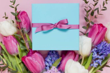 Güzel bir buket ve pembe arka planda kurdeleli mavi hediye kutusu. Fotokopi alanı ile tatil konsepti, metin için yer. 8 Mart, anneler günü teması