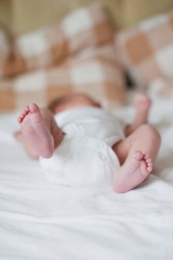 Yeni doğmuş bebek ayakları. Küçük çocuk yatakta yatıyor.