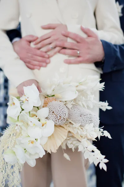 ダークブルーのスーツで新郎と手を保持ベージュの結婚式のスーツで花嫁 スタイリッシュな結婚式のコンセプト — ストック写真